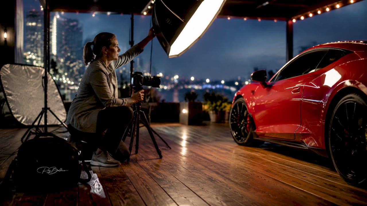 Photographer adjusting key light in car photo studio